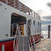 View of the gangway and the open bicycle storage on the hotel barge Ave Maria in the Venice Lagoon under a cloudy sky.