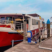The red and white hotel barge Ave Maria moored at a wooden pier in Venice, ready for the Bike & Boat tour to Mantua.