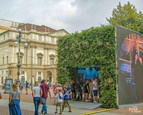 Experience Milan: Piazza della Scala during Milan Fashion Week • m24o Pedestrians at Piazza della Scala in Milan next to a green pavilion during the Fashion Fair, with the Teatro alla Scala in the background.