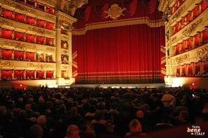 View of the occupied auditorium of the Teatro alla Scala in Milan with the magnificent red stage curtain before an opera performance.