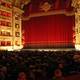 View of the occupied auditorium of the Teatro alla Scala in Milan with the magnificent red stage curtain before an opera performance.