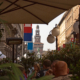 Perspective view of the pedestrian street Via Dante in Milan, featuring the Filarete Tower of Castello Sforzesco framed by historic buildings in the background.