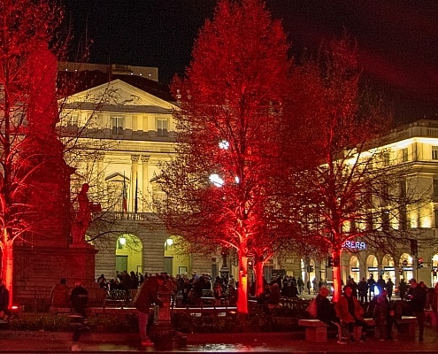 Festlich rot beleuchtete Bäume auf der Piazza della Scala in Mailand am Abend der großen Saisonpremiere des Teatro alla Scala.