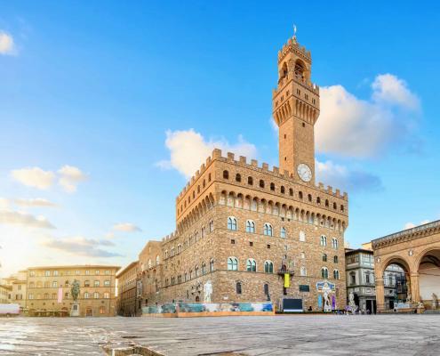 Florence, Italy. View of Piazza della Signoria square with Palazzo Vecchio reflecting in a puddle at sunrise