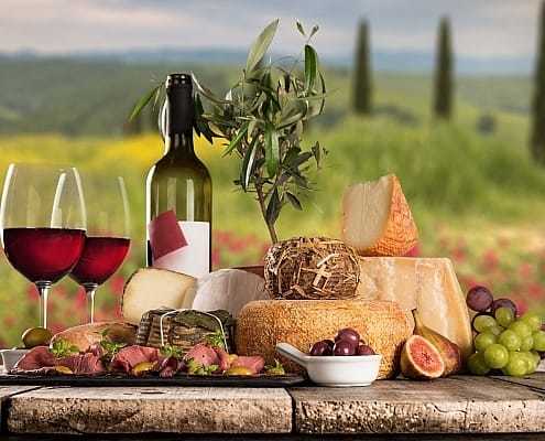 Delicious cheeses with wine in Tuscany • Kesu - stock.adobe.com Wine and cheese tasting on the city wall of Voltera looking out to the sea