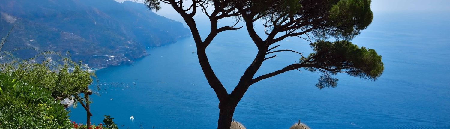 Klassischer Ausblick von der Villa Rufolo in Ravello mit der markanten Pinie, historischen Türmen und Blick auf die Amalfiküste.