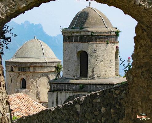 View through a stone archway in Ravello overlooking the picturesque Amalfi Coast with turquoise sea and lush mountains.