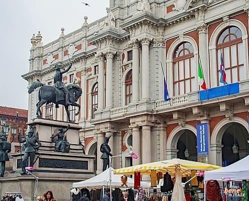Palazzo Carignano Turin Carlo Alberto Monument Book Market • m24o A vibrant book and art market in front of the baroque brick facade of Palazzo Carignano in Turin featuring the Carlo Alberto monument.