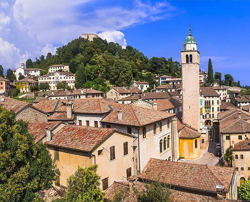 Daytime panoramic view of the medieval town of Asolo in Veneto, featuring the Rocca fortress against a clear sky.