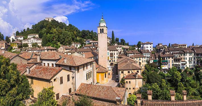 Daytime panoramic view of the medieval town of Asolo in Veneto, featuring the Rocca fortress against a clear sky.
