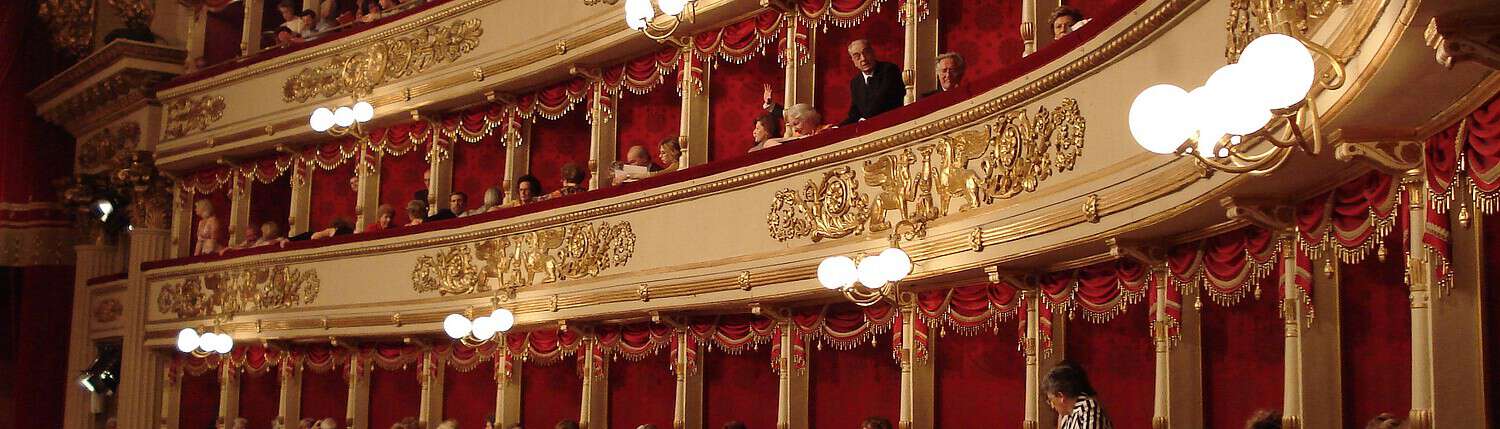 Private Boxes at Teatro alla Scala – Music Trips to Milan The historic gold-decorated boxes at Teatro alla Scala in Milan with red velvet lining and opera guests