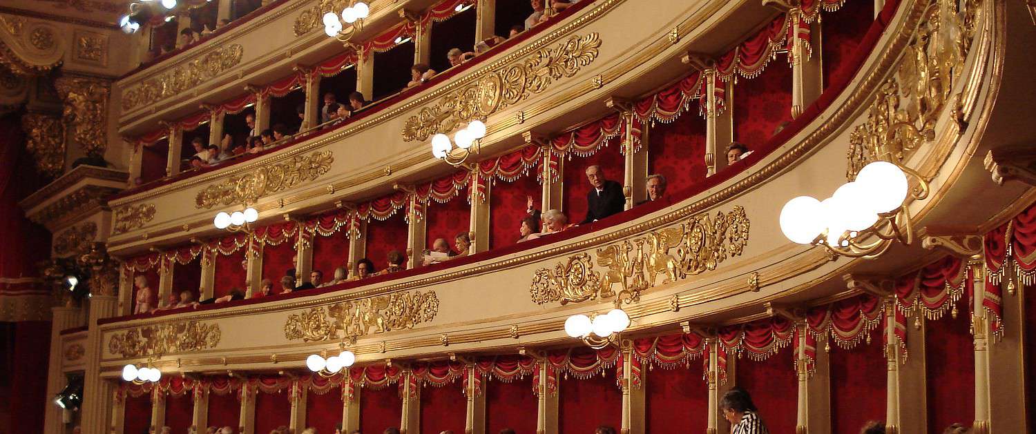 The historic gold-decorated boxes at Teatro alla Scala in Milan with red velvet lining and opera guests