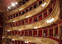 The historic gold-decorated boxes at Teatro alla Scala in Milan with red velvet lining and opera guests