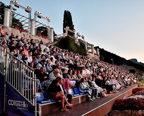 Classical concert at the Ravello Festival on the illuminated Villa Rufolo Belvedere stage at night overlooking the sea.