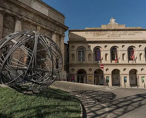 Exterior view of the Sferisterio in Macerata, a monumental historic open-air theatre in the Marche region, which serves as the main stage of the Macerata Opera Festival. The long façade with its round-arched arcades and neoclassical architecture dominates the square and reflects its original use as a sports arena as well as its current importance as an opera venue.
