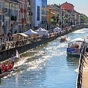 View along the Naviglio Grande in Milan featuring historic colorful houses reflecting in the canal waters.