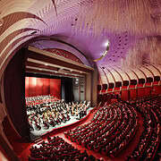 Teatro Regio Torino Opera Interior Stage • Foto Edoardo Piva Wide view of the stage with orchestra and choir inside the packed auditorium of Teatro Regio di Torino featuring its modern purple ceiling.