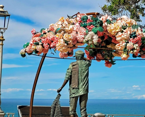 Bronze statue of a fisherman pulling a net at the Piazzetta della Torre in Numana, Marche region, Italy.