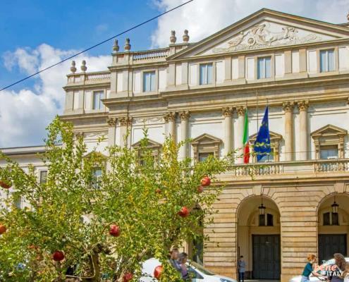 Experience Art and History: Teatro alla Scala and its Museum • m24o Exterior view of the Teatro alla Scala in Milan with a pomegranate tree in the foreground; the building also houses the famous theater museum.