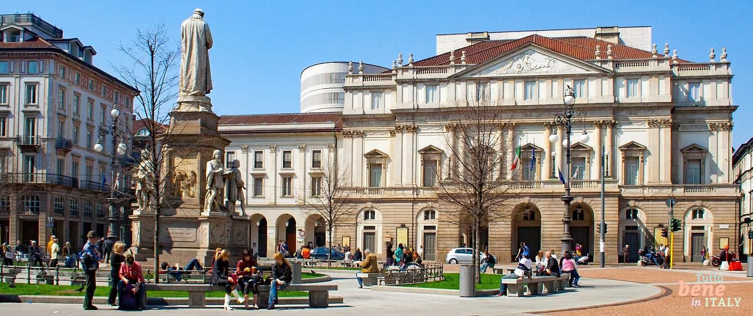 Das Teatro alla Scala an der Piazza della Scala in Mailand mit dem Leonardo-da-Vinci-Denkmal und Besuchern an einem sonnigen Tag.