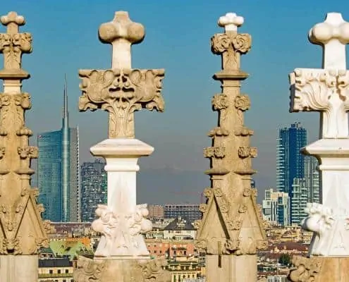 The skyline of Milan between the statues of the cathedral rooftop