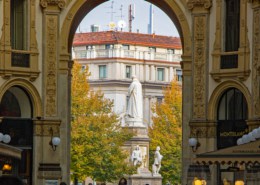 View through the grand arch of Galleria Vittorio Emanuele II onto the Leonardo da Vinci monument and the autumnal Piazza della Scala in Milan.