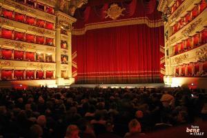 Der Saal der Scala in rotem Samt • m24o Der festlich beleuchtete Zuschauerraum des Teatro alla Scala in Mailand mit dem ikonischen roten Vorhang und erwartungsvollem Publikum.
