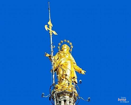 The Golden Madonnina atop Milan Cathedral • m24o Close-up of the gilded Madonnina statue on the highest spire of the Milan Cathedral against a clear blue sky.