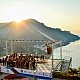 Ein Sinfonieorchester spielt beim Ravello Festival auf der B&uuml;hne der Villa Rufolo Belvedere, w&auml;hrend die Sonne hell &uuml;ber dem Berg der Amalfik&uuml;ste aufgeht.