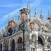 St. Mark's Basilica – The Golden Wonder of Venice • m24o The magnificent facade of St. Mark's Basilica in Venice featuring its golden mosaics and a historic street lamp in the foreground.