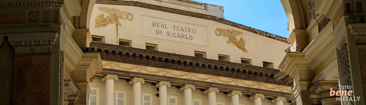 Blick auf das Teatro di San Carlo von der Galleria Umberto I Die Inschrift „Real Teatro di S. Carlo“ an der Fassade des Opernhauses in Neapel, eingerahmt von den kunstvollen Bögen der Galleria Umberto I unter blauem Himmel.