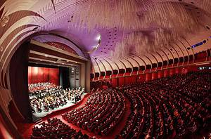 Teatro Regio Torino Opera Interior Stage Wide view of the stage with orchestra and choir inside the packed auditorium of Teatro Regio di Torino featuring its modern purple ceiling.