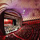Wide view of the stage with orchestra and choir inside the packed auditorium of Teatro Regio di Torino featuring its modern purple ceiling.