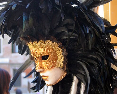 Venetian Mask Magic – Mysterious Carnival in the Lagoon City • m24o A magnificent Venetian Carnival mask in gold and white, adorned with an opulent headpiece of black feathers.